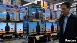 A man walks past televisions sets displaying a news program about an Islamic State video purporting to show two Japanese captives at an electronics store in Tokyo on January 20.