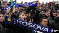 Supporters of the Kosovo soccer team holding scarves reading "Kosovo" cheer in the stands during a friendly match between Kosovo and Haiti in Mitrovica in March 2014.