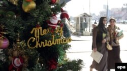 Iraqi women look at a Christmas tree outside a Baghdad shop.