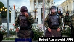 A Macedonian police officer tries to remove red paint from his helmet's visor after protesters threw balloons filled with colored paint during an antigovernment protest in Skopje on June 6. 