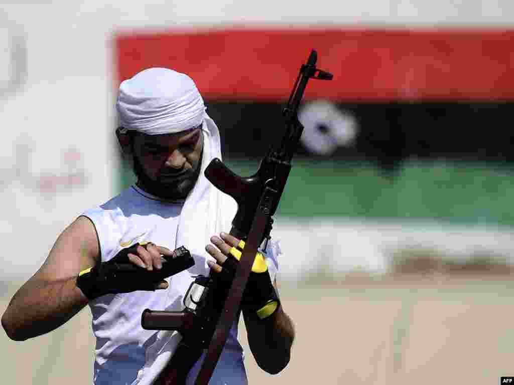 A rebel fighter reloads his gun on the streets of Tripoli