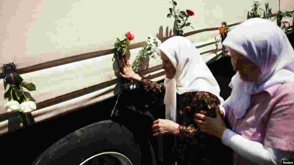 A woman touches one of the three trucks carrying the slain victims of the 1995 Srebrenica massacre in front of the presidential building in Sarajevo on July 9.