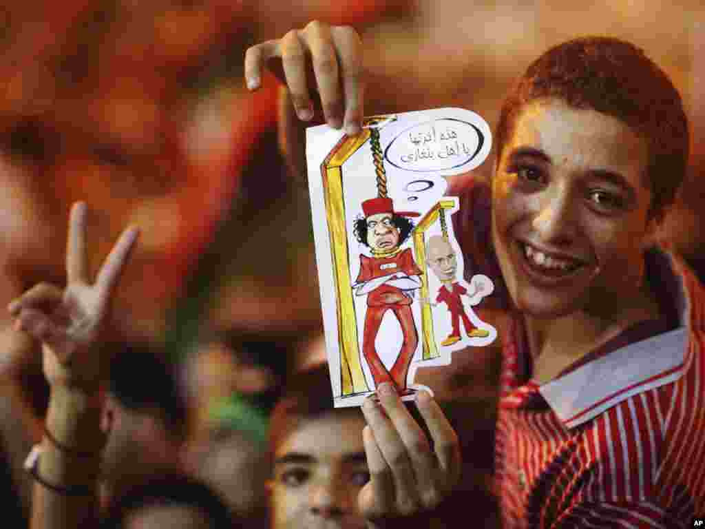  A boy holds a drawing of Qaddafi and his son Seif al-Islam on the gallows during celebrations of the fall of Tripoli. - 