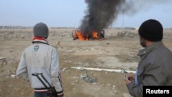 Sunni Muslim fighters watch as a police vehicle burns during clashes in the Iraqi city of Ramadi on January 2. Militants have seized control of large parts of Ramadi and Fallujah amid sectarian violence in recent days. 