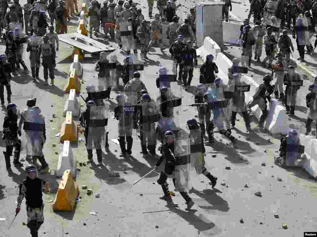 Riot policemen shield themselves from rocks being hurled at them in downtown Baghdad.