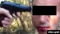 A screen shot from a video purportedly showing a man being threatened at gunpoint while being forced to sodomize himself with a bottle.