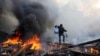 A man walks amid burning remains of barricades on Independence Square in Kyiv on February 21.