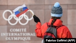 A supporter waves a Russian flag in front of the logo of the International Olympic Committee at their headquarters near Lausanne. (file photo)