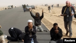 Rebel fighters pray during a battle near Ras Lanuf.