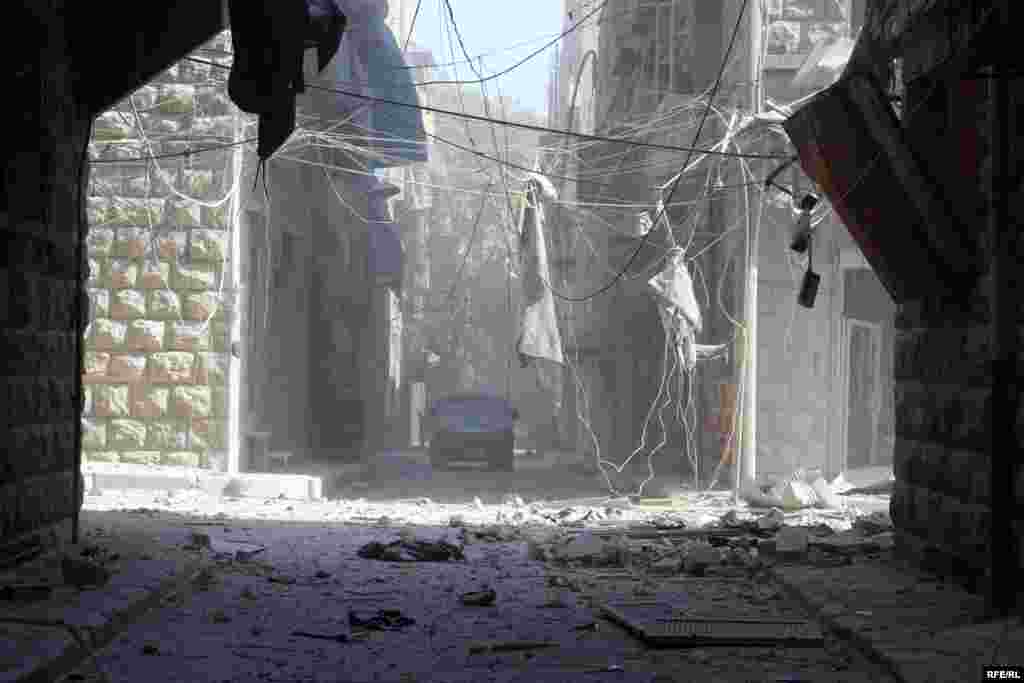 A vehicle navigates through the debris-clogged streets of Aleppo&#39;s Bustan al-Qasr district. Following air strikes on October 11, many streets were littered with bricks from bombed-out buildings and webs of tangled wires.