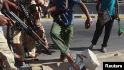 Libyan rebel fighters step on a picture of Muammar Qaddafi at a checkpoint in Tripoli on August 22.