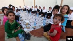 A group of young Afghans wait to eat iftar, the meal traditionally taken after sunset prayers to break the fast during the Islamic holy fasting month of Ramadan, in Herat.