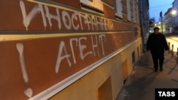 A man walks past graffiti reading "Foreign agents. I love USA" on the building used by used by the Memorial Human Rights Center in Moscow.