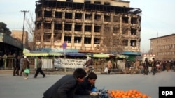 Afghans pass by a shopping mall in Kabul that was the scene of a gunbattle between Taliban militants and goverment forces a day earlier.