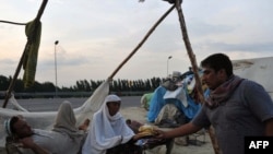 A Pakistani commuter offers bread to flood survivors on a roadside in Charsadda, Pakistan on August 12.