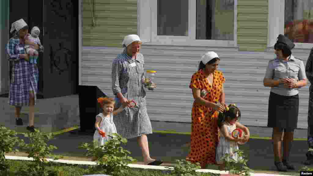 Inmates walk with their children as a guard watches in the courtyard of a &quot;children&#39;s home,&quot; located inside a female prison camp in the Siberian city of Krasnoyarsk. 