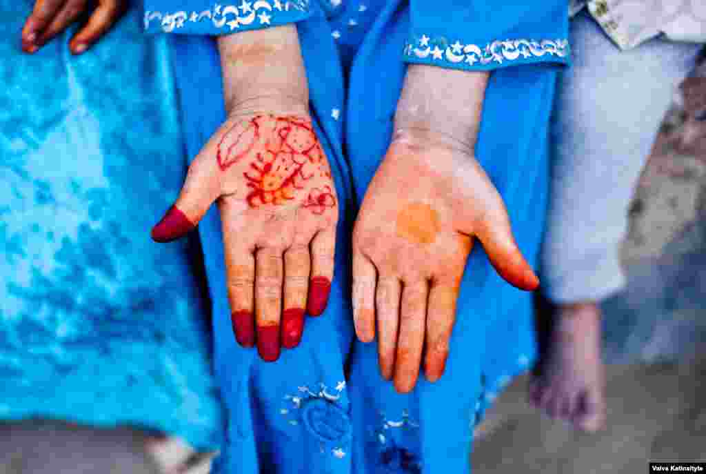 A refugee woman shows henna decorations on her hands.