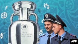 Ukrainian police officers pass a placard depicting the Euro 2012 trophy on Independence Square in Kyiv.