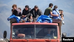 Refugees from Nagorno-Karabakh ride on a truck arriving at the border village of Kornidzor, Armenia, on September 27.