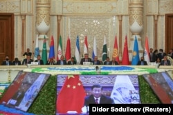 Participants listen to Chinese President Xi Jinping deliver a speech via a video link during a Shanghai Cooperation Organization summit in Dushanbe on September 17, 2021.