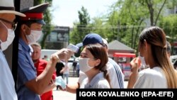 A security guard in a shopping center in the Kyrgyz capital, Bishkek, measures the temperature of visitors.