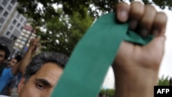 A supporter of Iranian presidential candidate Mir Hossein Musavi waves a green ribbon -- Musavi's campaign color -- during protests in Tehran on June 13.