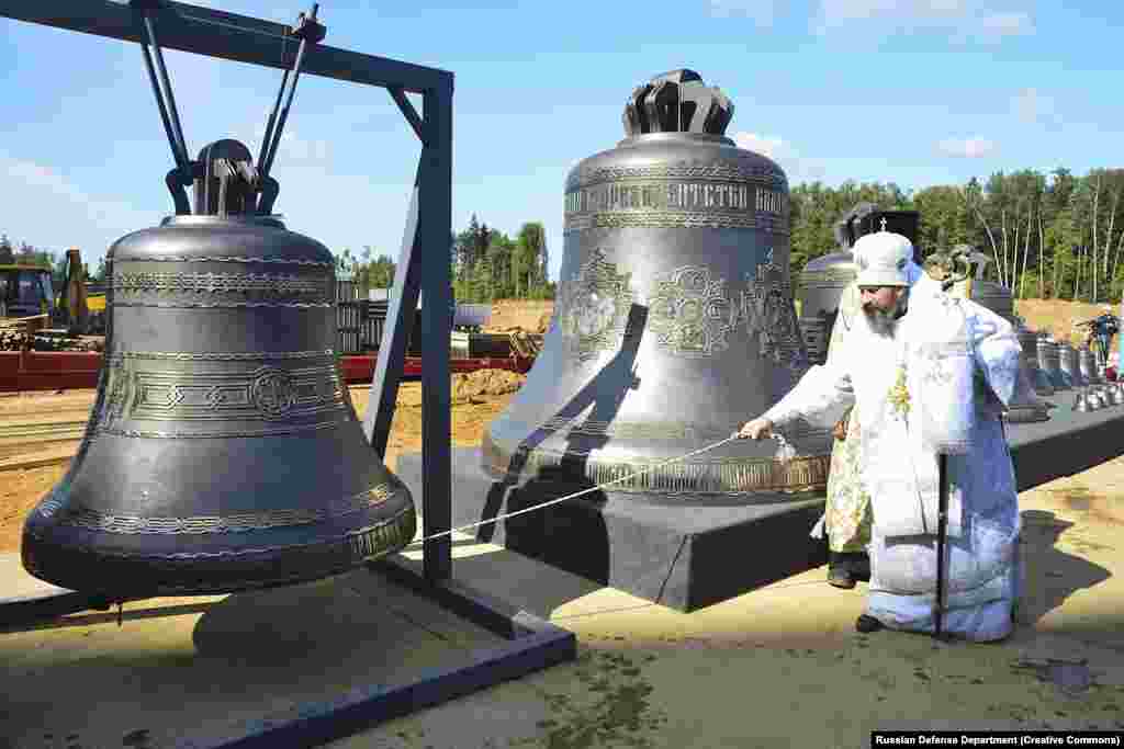 Some of the bells that have since been installed in the church belfry being tested by a priest in August 2019. The largest bell (center) weighs around 10 tons.