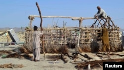 Survivors of the September 24 earthquake use poles to build a makeshift shelter near the rubble of a mud house after it collapsed in the Awaran district of Balochistan Province.