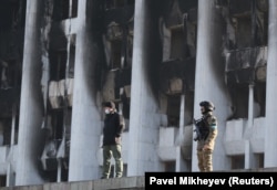 Kazakh soldiers stand guard outside the city administration headquarters, which was set on fire during protests triggered by an increase in fuel prices, in Almaty on January 12.