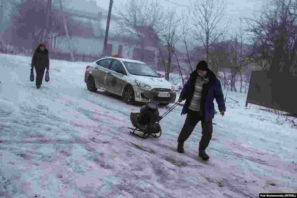 Residents of Debaltseve haul a small supply of drinking water from a tanker truck.