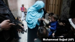 A policeman guards a health worker as she gives a polio vaccination to a child in Peshawar in December 2019.