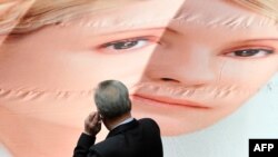 A member of the Ukrainian parliament looks at a giant placard on April 25 depicting former Prime Minister Yulia Tymoshenko set by the opposition in the parliament's sitting hall.