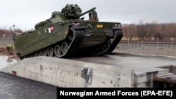 A Norwegian CV9030 armored infantry combat vehicle drives up a ramp and on to a train during thee NATO-led Trident Juncture exercises in Stjordal, Norway, on October 24.