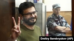 Ilya Yashin gestures from inside a defendants' cage during a court hearing in Moscow in July.