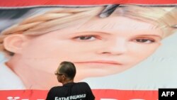 An opposition lawmaker stands next to a giant poster featuring Yulia Tymoshenko in the parliament in Kyiv on September 6.