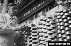 A store worker stacks cans of sardines in 1950.