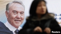 A woman walks past an election poster of Kazakh President Nursultan Nazarbaev in Almaty on February 22.