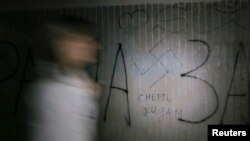 A woman walks past a swastika and the inscription "Death to Jews' painted on a wall in an underpass in Kyiv. File photo