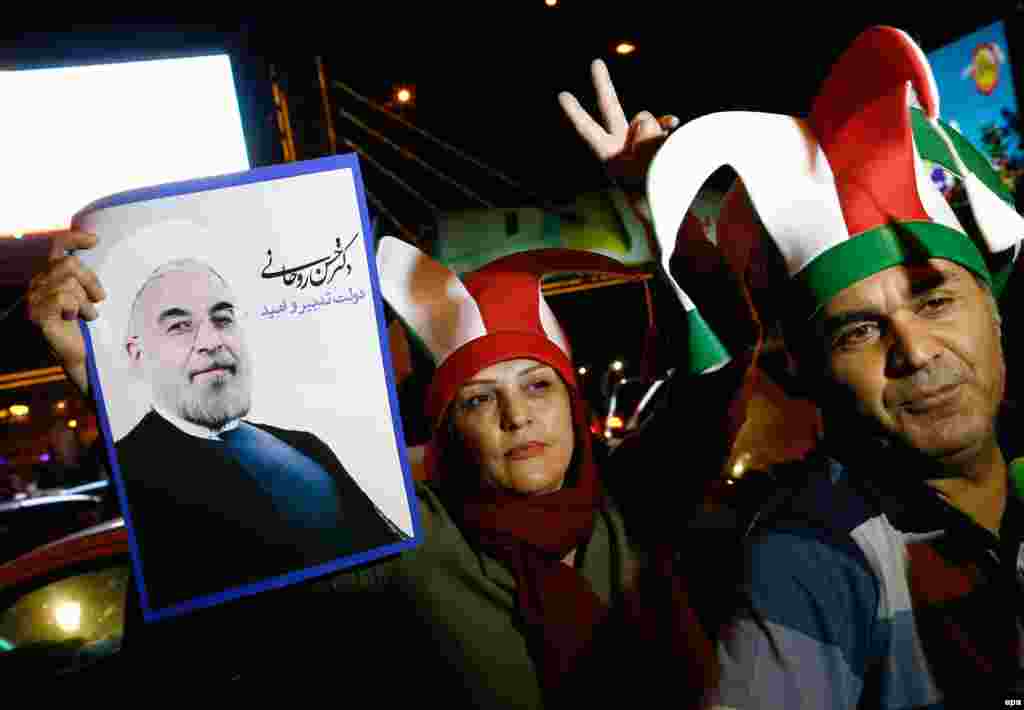 A couple holds a poster of Iranian President Hassan Rohani, who said that the nuclear deal would open a new chapter of international cooperation after years of sanctions.