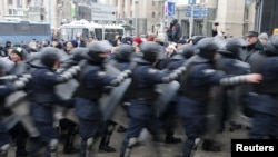 A line of Ukranian riot police moves past protesters in Independence Square in Kyiv.