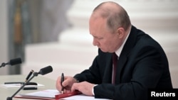 Russian President Vladimir Putin signs documents, including a decree recognizing two Russian-backed separatist formations in eastern Ukraine as independent entities during a ceremony in Moscow on February 21. 