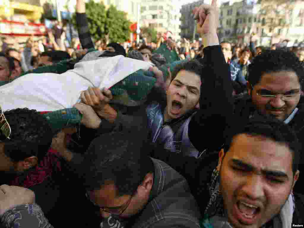 Demonstrators carry the body of a man killed during an attempt to storm the interior Ministry in Cairo.