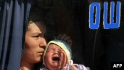 A mother and her child, who fled their home city during the violence, sit in a bus with "Osh" written on the window as they prepare to return home.