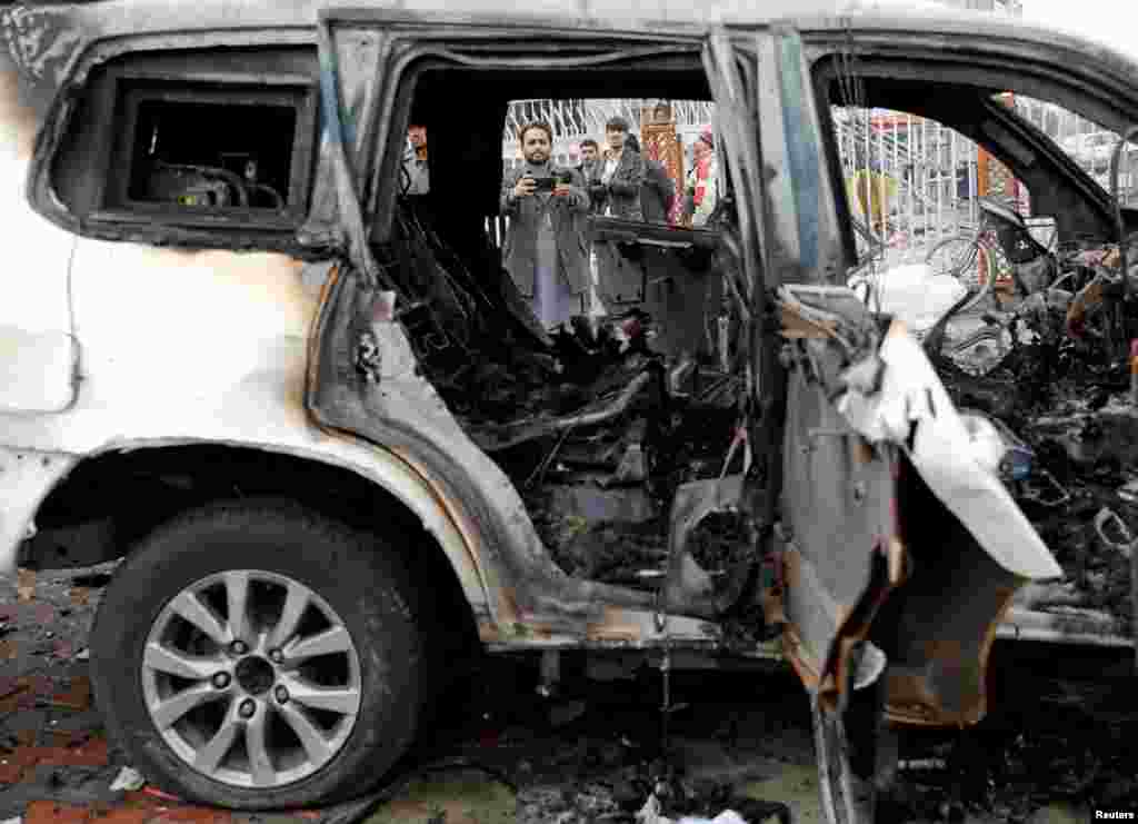 An Afghan journalist films a damaged vehicle at the site of a blast in Kabul on December 20.