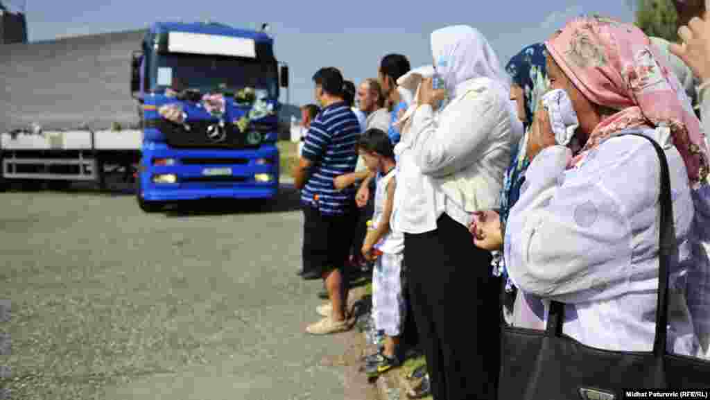 Bosnians watch as one of the trucks carrying some of the Srebrenica victims arrives in Potocari, where they will be buried, on July 9.