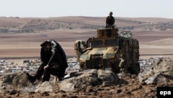 Turkish soldiers on duty as a man watches from a hill in Turkish territory during fighting between Syrian Kurdish fighters and Islamic State militants.