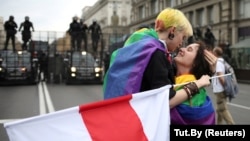 Protesters with rainbow-themed flags embrace near barriers erected by Belarusian police during an opposition rally against police brutality and the presidential election results in Minsk on September 6, 2020.