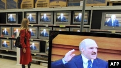 A woman watches as President Alyaksandr Lukashenka gives his annual address on television at a Minsk electronics store.