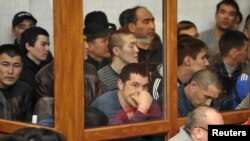 Defendants in Zhanaozen riots case look out of a glass cubicle during a court session in the Caspian port city of Aqtau on March 27.