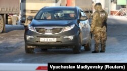 A Ukrainian border guard checks a car with a Russian license plate at the Goptovka crossing point on the border between Russia and Ukraine in the Kharkiv region on November 30.